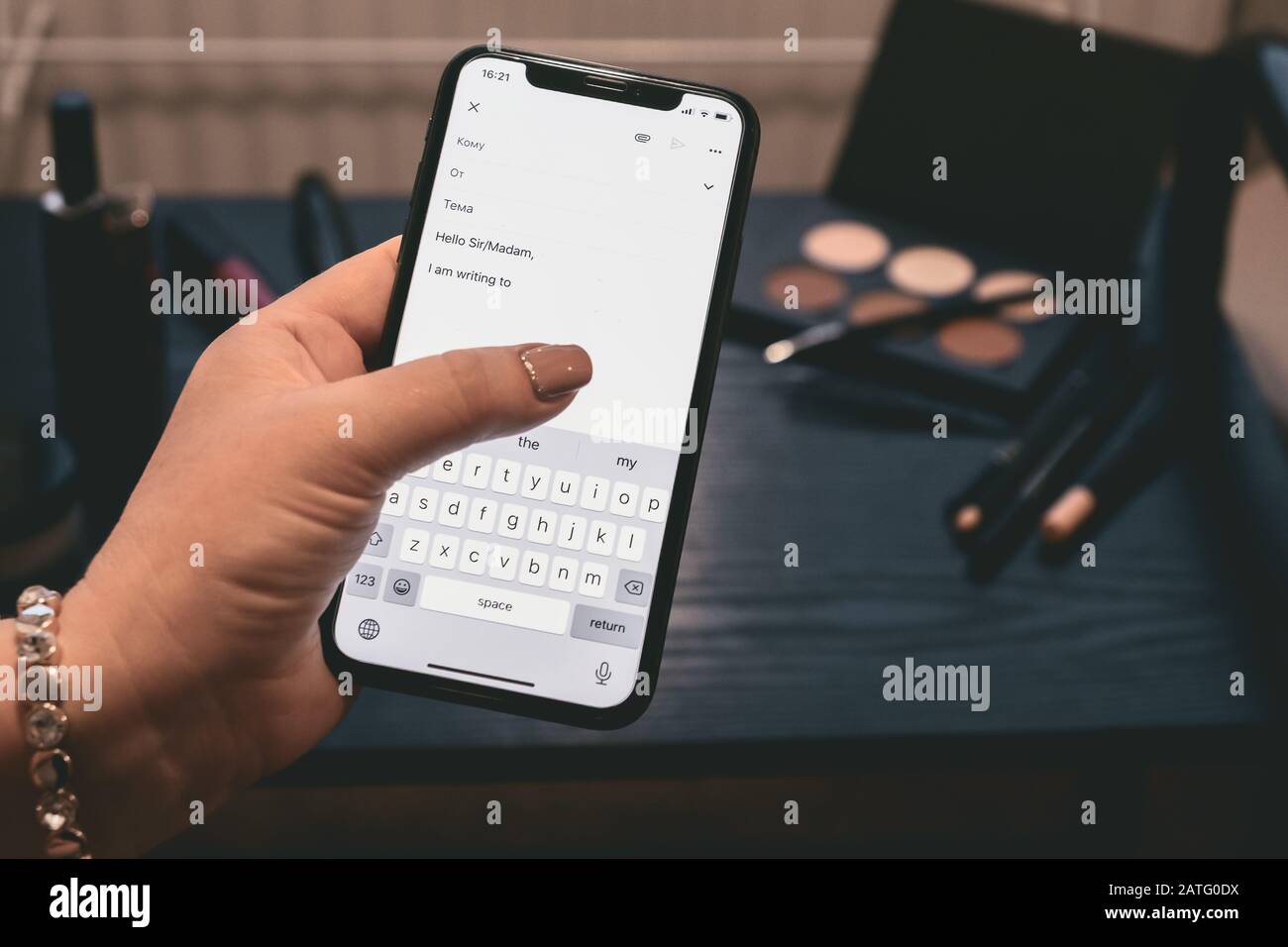 Primo piano di una donna che tiene lo smartphone, digita il testo sullo schermo a sfioramento e utilizza le applicazioni. La mano è sullo sfondo della medicazione blac Foto Stock