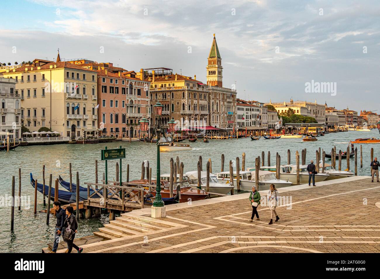 La gente passa davanti alla stazione della gondola a Fondamenta Salute, con il Campanile di San Marco o il Campanile in distanza Foto Stock