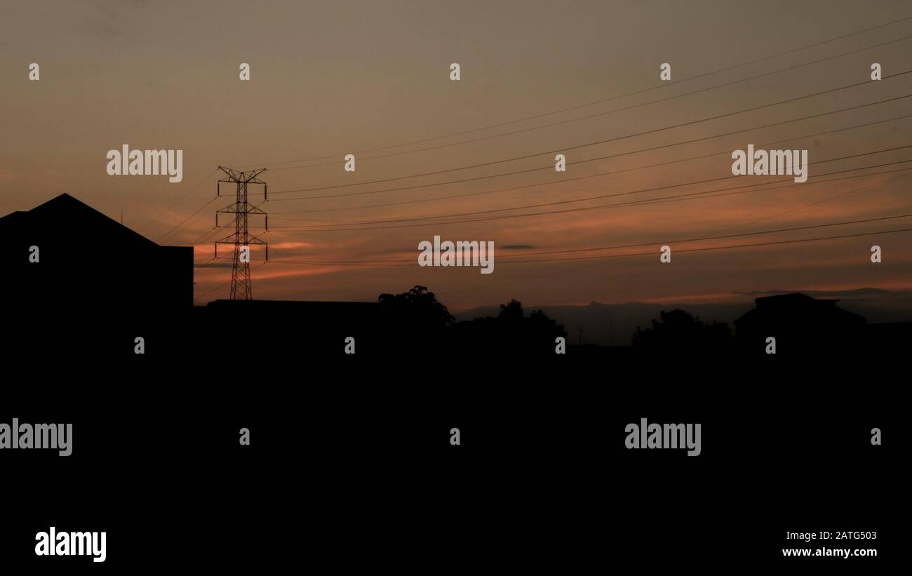 Cantiere e polo elettrico con Sunrise SKY, silhouette di palo elettrico ad alta tensione all'alba o al tramonto Foto Stock