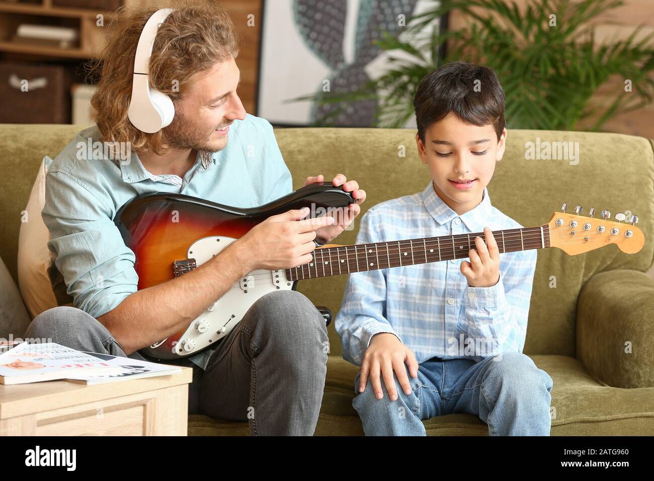 L'uomo insegnò al figlio piccolo a suonare la chitarra a casa Foto Stock