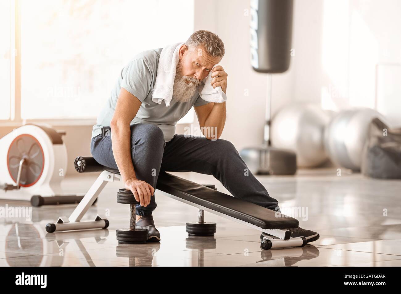 Uomo anziano sportivo che riposa dopo la formazione in palestra Foto Stock