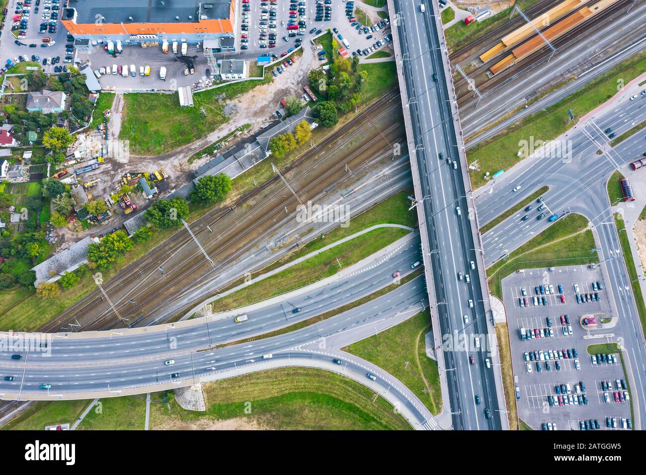 veduta aerea dall'alto verso il basso di un ponte stradale che attraversa una ferrovia. traffico automobilistico su strada nell'area industriale urbana Foto Stock