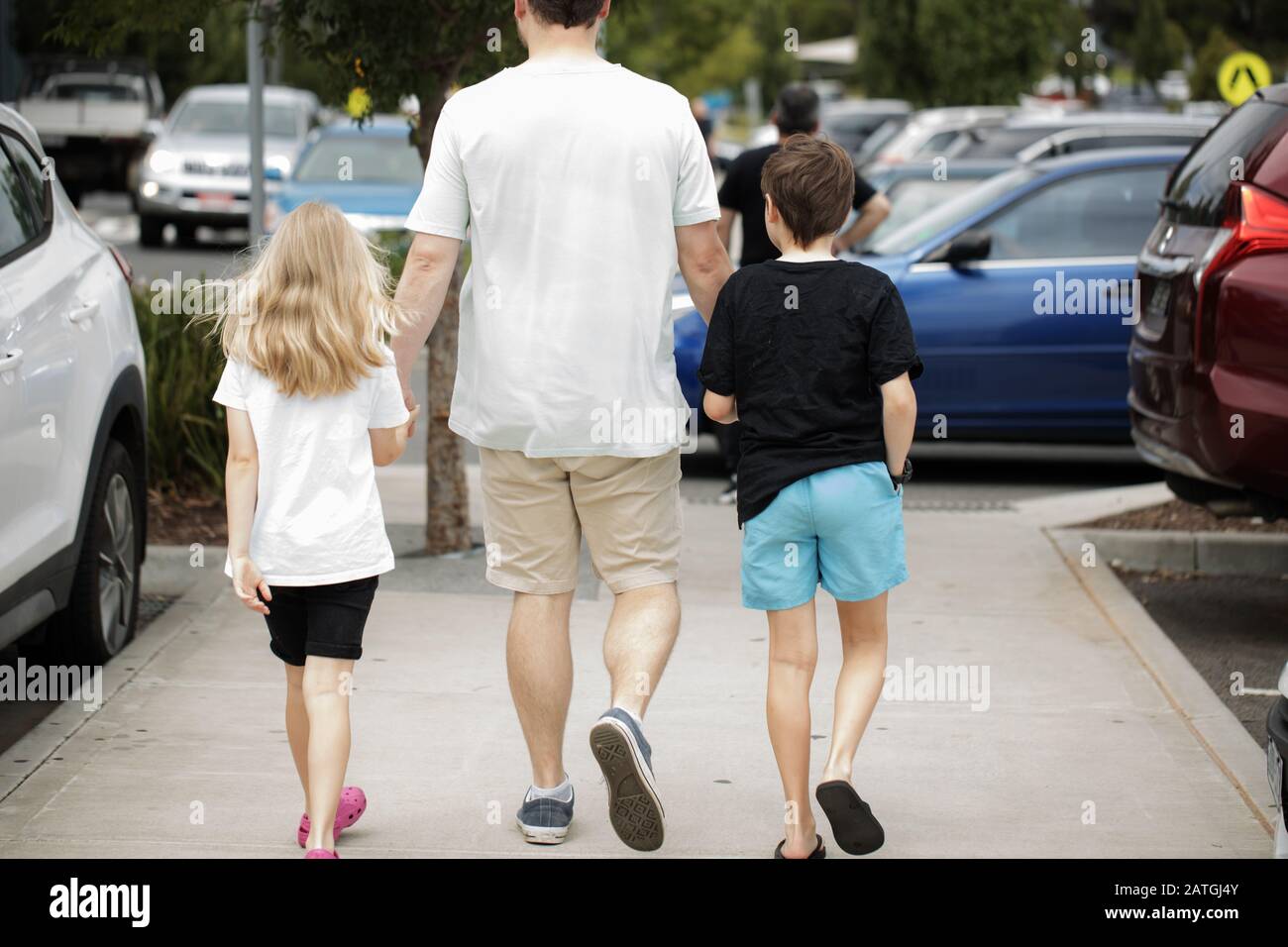 padre che cammina con i bambini, tenendo le mani Foto Stock