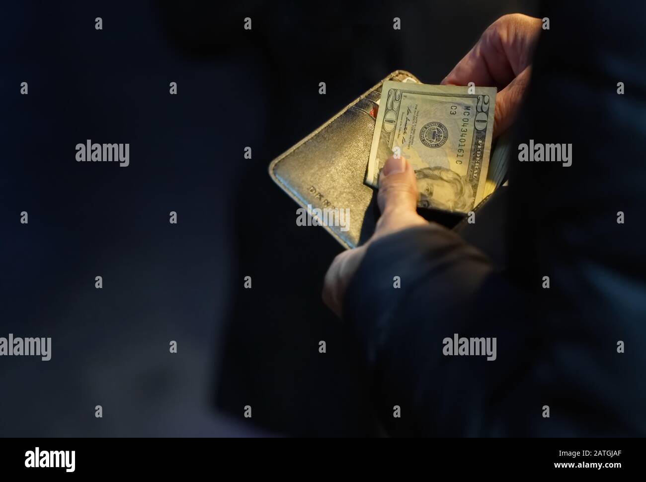 New York, NY / USA - 29 dicembre 2019: Primo piano di mani che prendono una fattura di venti dollari da un portafoglio di pelle nera Foto Stock
