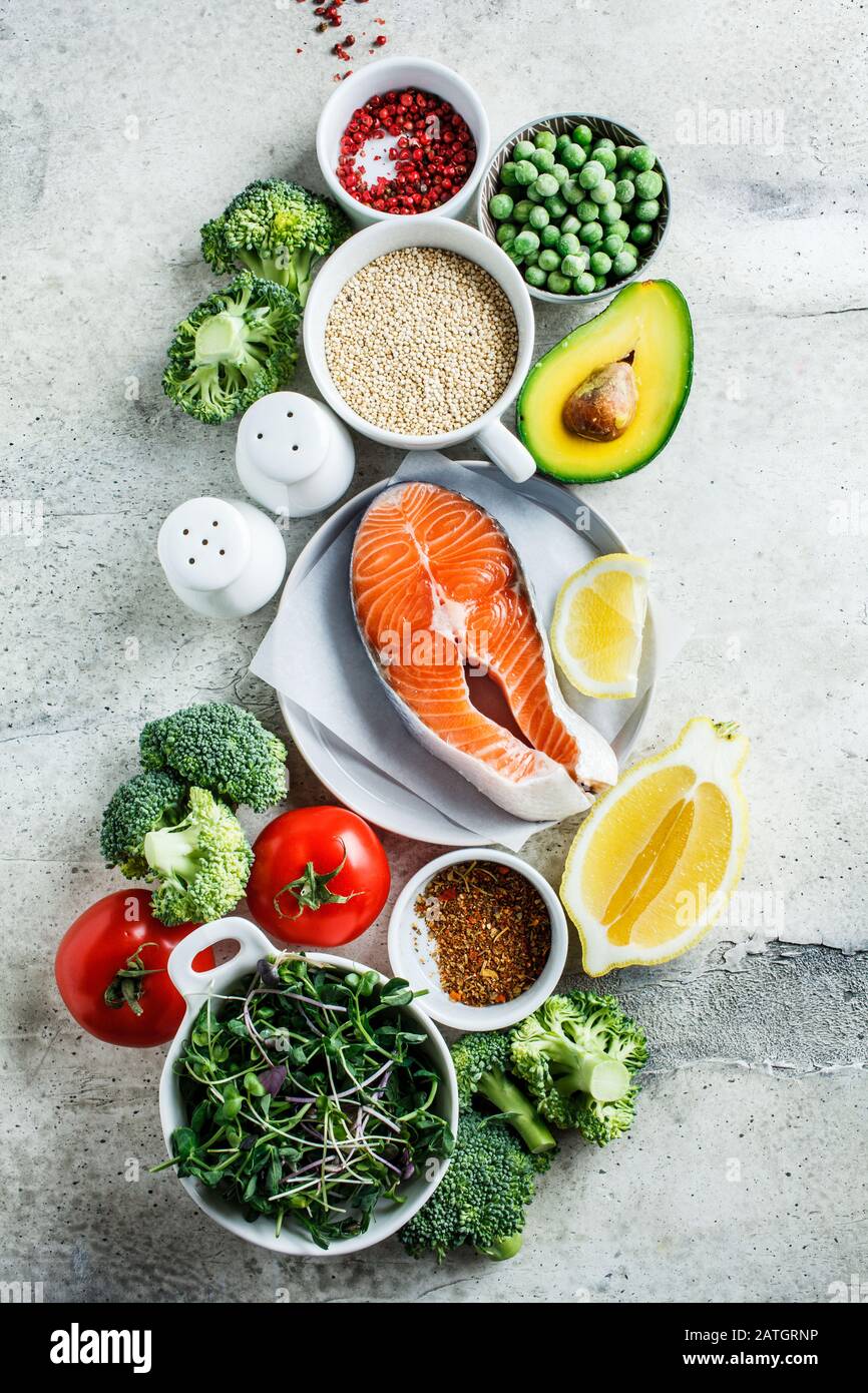 Salmone crudo con broccoli, quinoa e avocado su sfondo grigio, vista dall'alto. Bistecca di salmone e ingredienti. Contesto alimentare equilibrato. Foto Stock