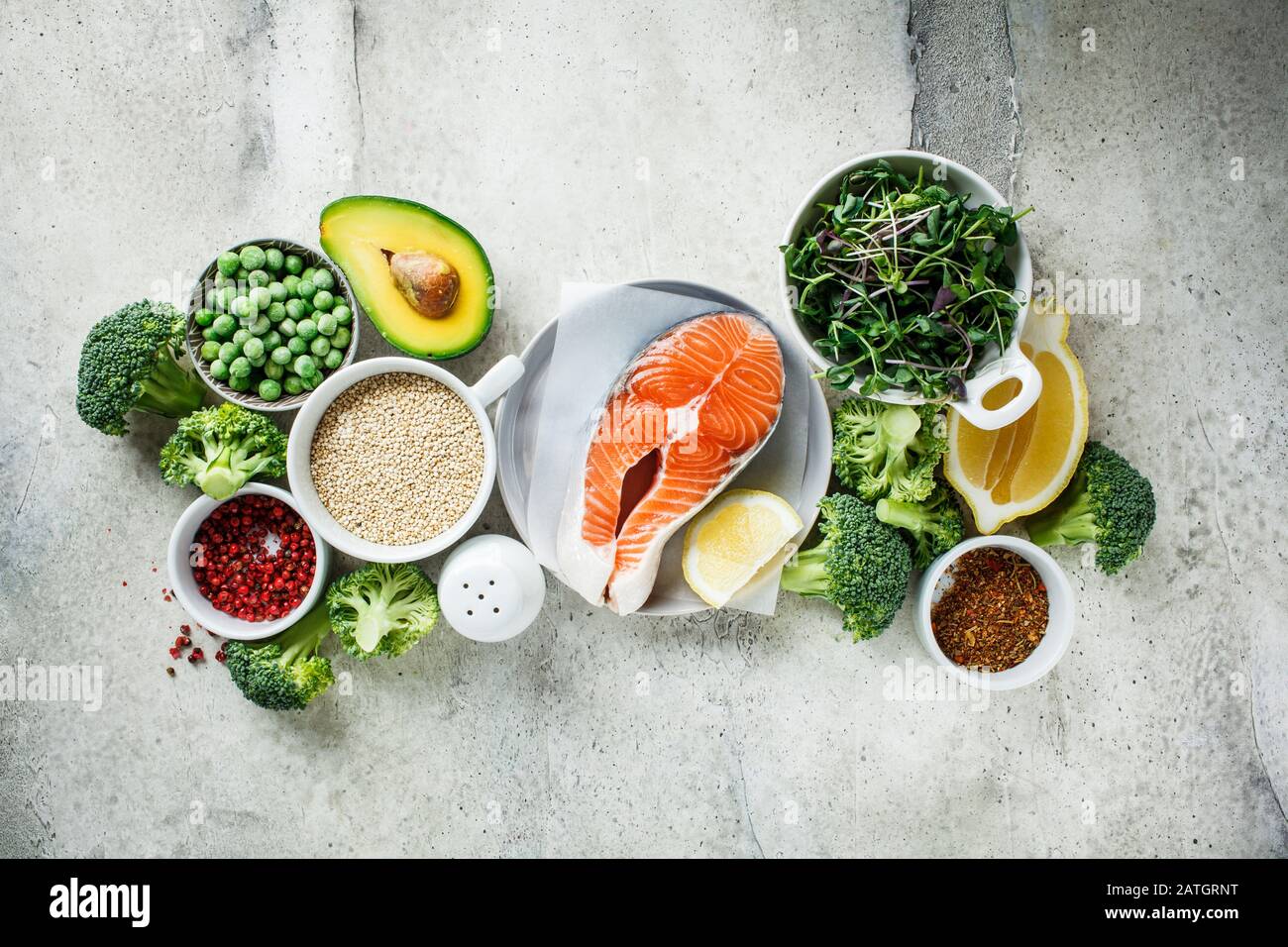Salmone crudo con broccoli, quinoa e avocado su sfondo grigio, vista dall'alto. Bistecca di salmone e ingredienti. Contesto alimentare equilibrato. Foto Stock