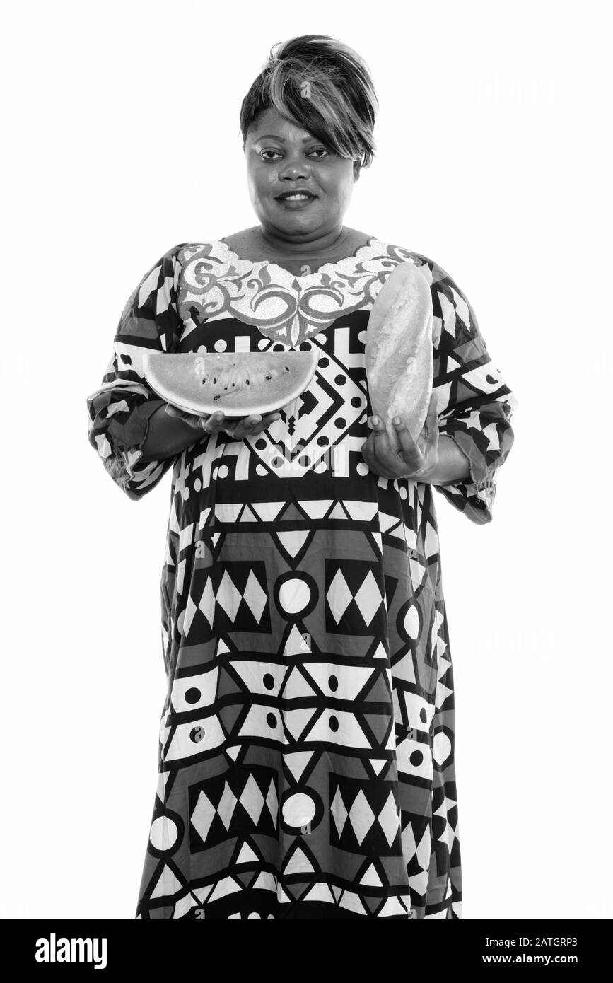 Felice donna africana in sovrappeso che detiene pane e fetta di cocomero Foto Stock