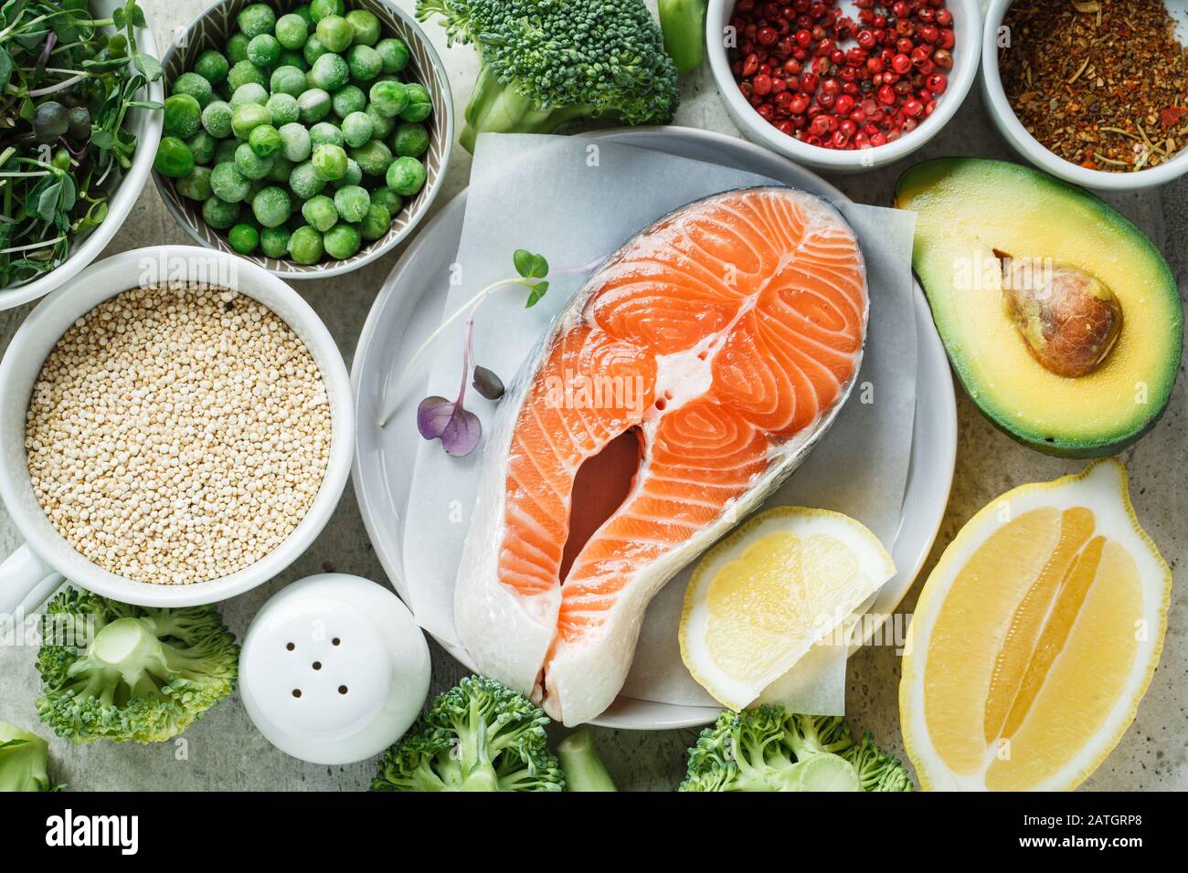 Salmone crudo con broccoli, quinoa e avocado su sfondo grigio, vista dall'alto. Bistecca di salmone e ingredienti. Contesto alimentare equilibrato. Foto Stock