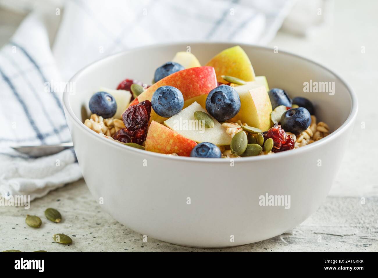 Bircher muesli o farinata d'avena da notte con mela, banana e mirtilli in una ciotola grigia. Foto Stock