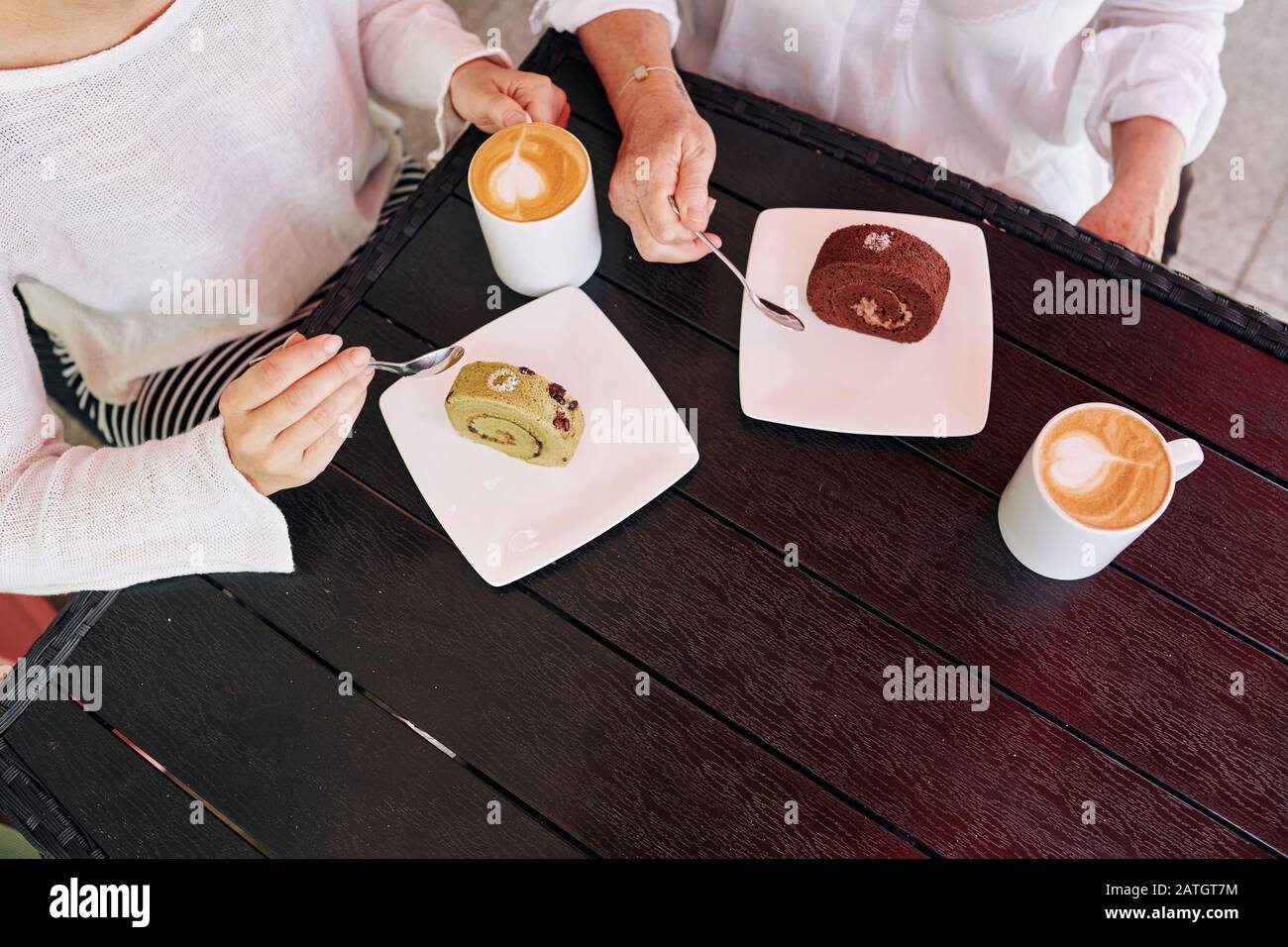 Madre e figlia che mangiano panini svizzeri e che bevono cappuccino nel caffè locale, vista dall'alto Foto Stock