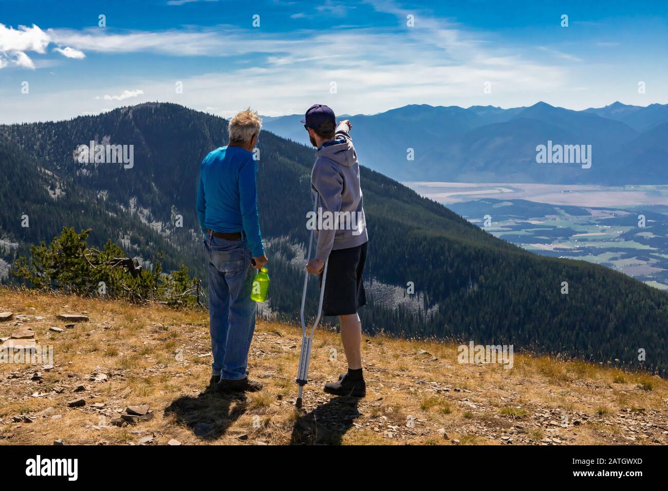 Due amici che discutono il piano di volo sul deltaplano. Un bellissimo paesaggio collinare. Escursionisti extremal che guardano la bella vista panoramica Foto Stock