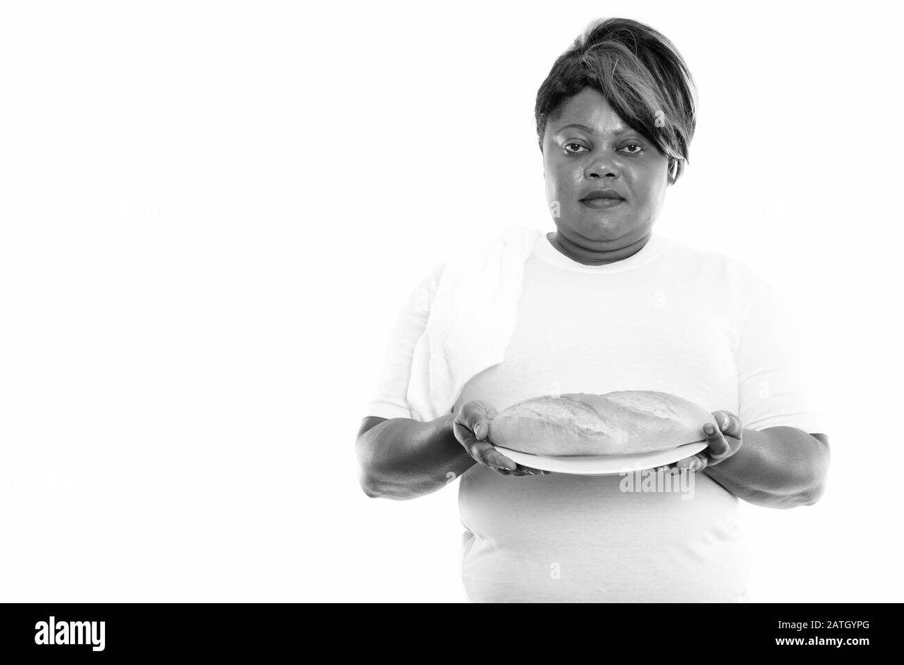 Monolocale di grasso nero donna africana che tiene il pane servito su piatto bianco pronto per la palestra Foto Stock