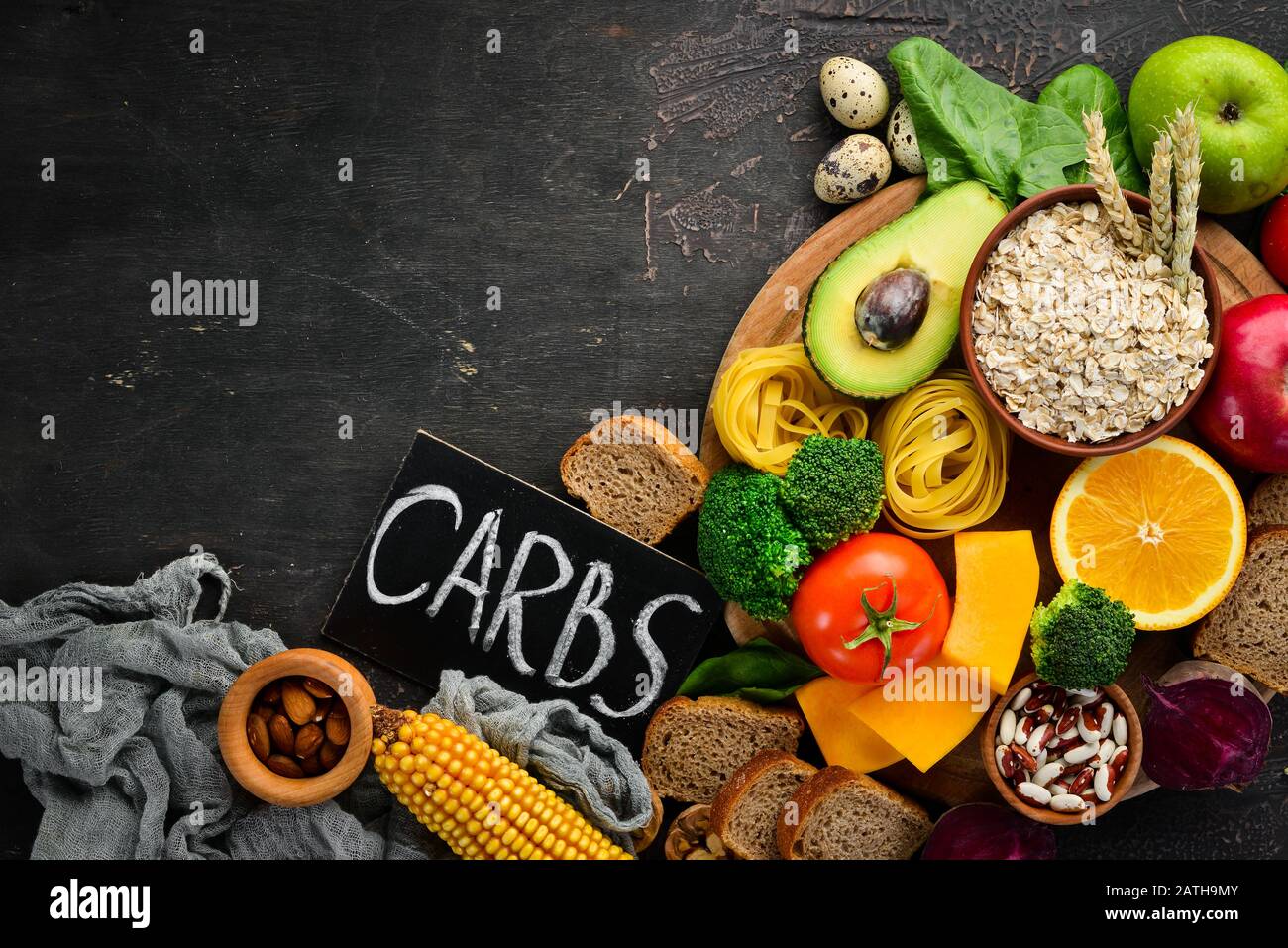 Alimenti con carboidrati naturali: Pane, pasta, avocado, farina, zucca, broccoli, fagioli, spinaci. Su sfondo marrone. Vista dall'alto. Spazio libero di copia. Foto Stock