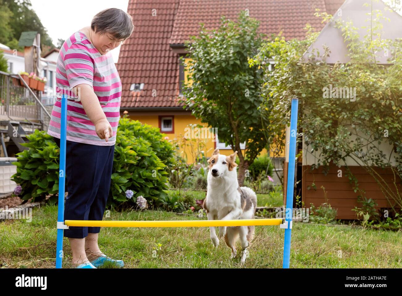 la donna mentale disabile sta facendo agilità con un cane carino all'aperto nel giardino Foto Stock