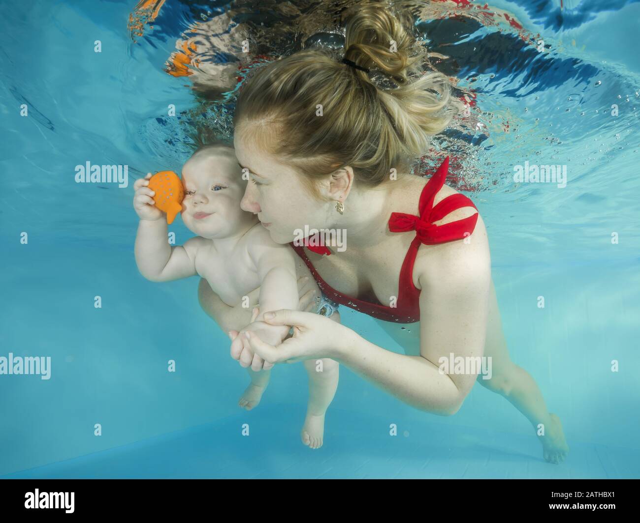 Mamma con un piccolo figlio si tuffa sott'acqua in una piscina Foto Stock