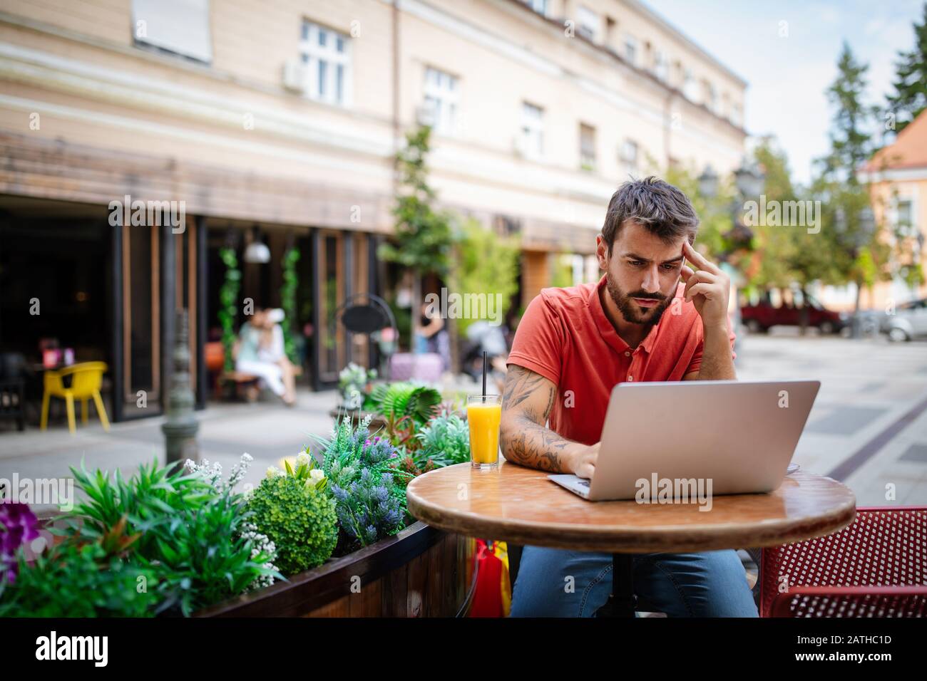 Giovane uomo stressato e stanco seduto di fronte al computer portatile nel caffè Foto Stock