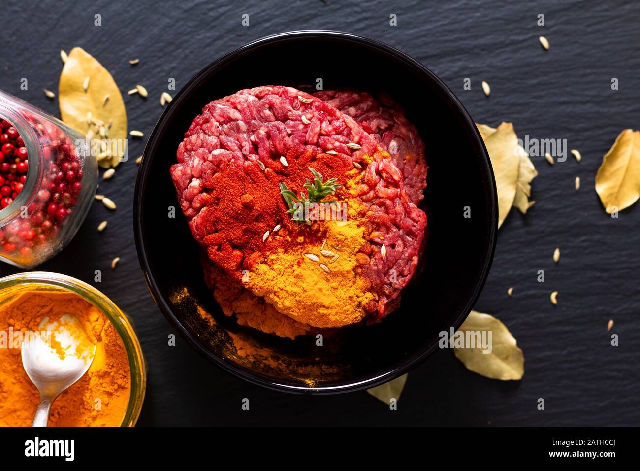 Preparazione alimentare ingredienti concetto organico crudo tritato o macinato di manzo marinato con spezie per cibo orientale curry Keema su pietra di ardesia nera con c Foto Stock