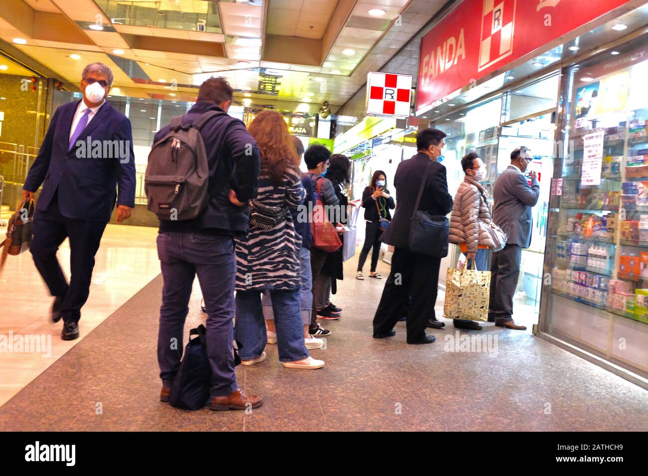 La gente fila fino ad ottenere le maschere alla farmacia in Hong Kong.Hong Kong la situazione epidemica ha colpito duro economico. Il Segretario finanziario Paul Chan ha affermato che Hong Kong potrebbe registrare un deficit di bilancio quest'anno. Foto Stock