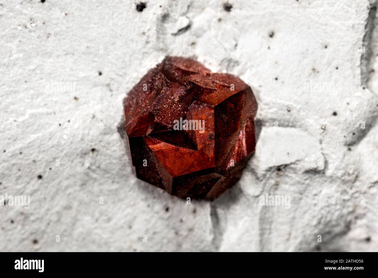 Primo piano di una pietra minerale granato su roccia madre, sfondo modello con dettagli di mineralogia Foto Stock