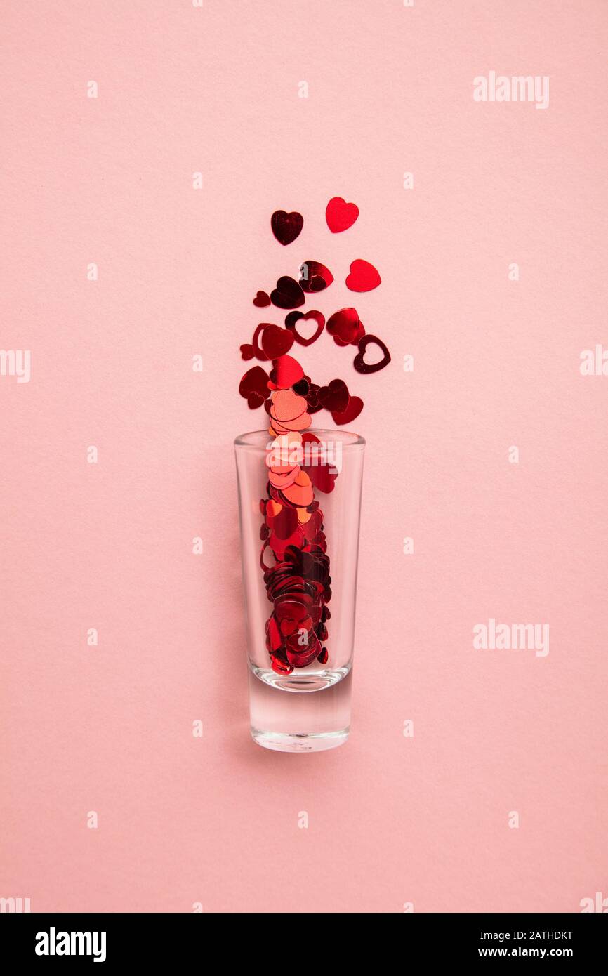 Foto di San Valentino. Bicchierino con confetti di cuore su sfondo rosa pastello Foto Stock