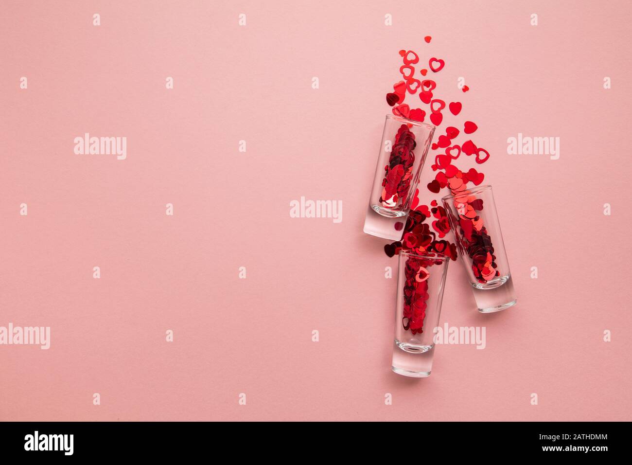 Foto di San Valentino. Bicchierino con confetti di cuore su sfondo rosa pastello Foto Stock