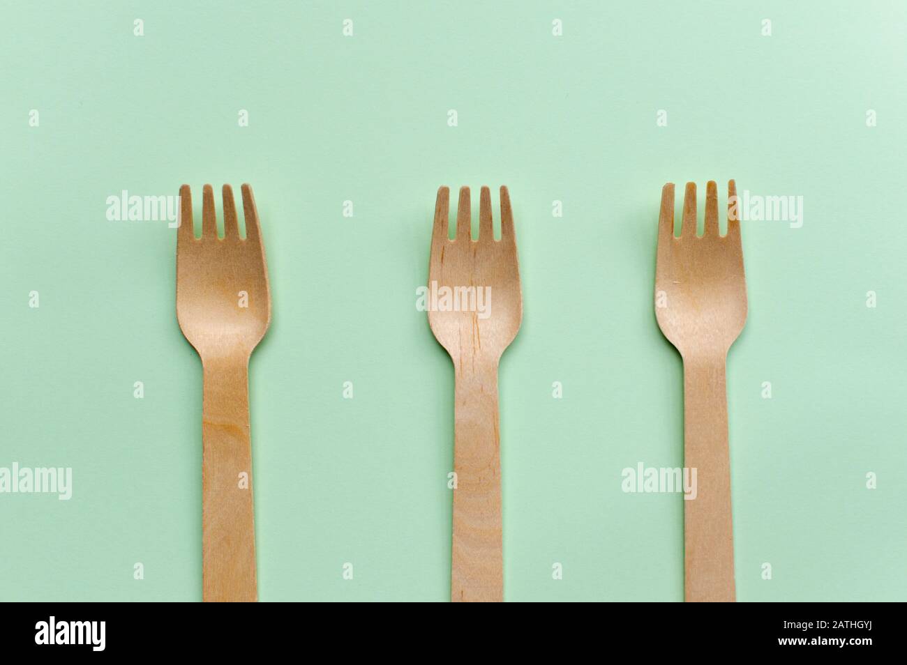 Tre forchette monouso in legno su sfondo verde, concetto ecologico Foto Stock