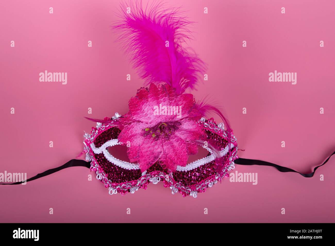 Elegante maschera veneziana di colore fucsia su sfondo rosa. Prendere dall'alto. Concetto di festa Foto Stock