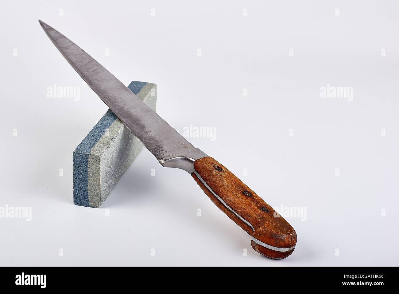 vecchio coltello usato cuoco, su una pietra per affilatura, sfondo bianco Foto Stock