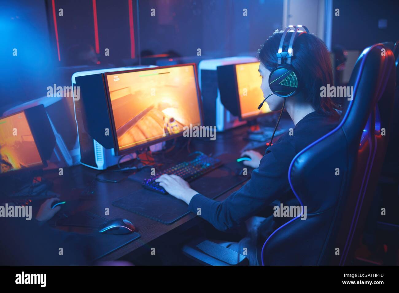 Vista ad alto angolo al giovane asiatico che gioca ai videogiochi e indossa le cuffie negli interni del cyber sport scuro, copia spazio Foto Stock