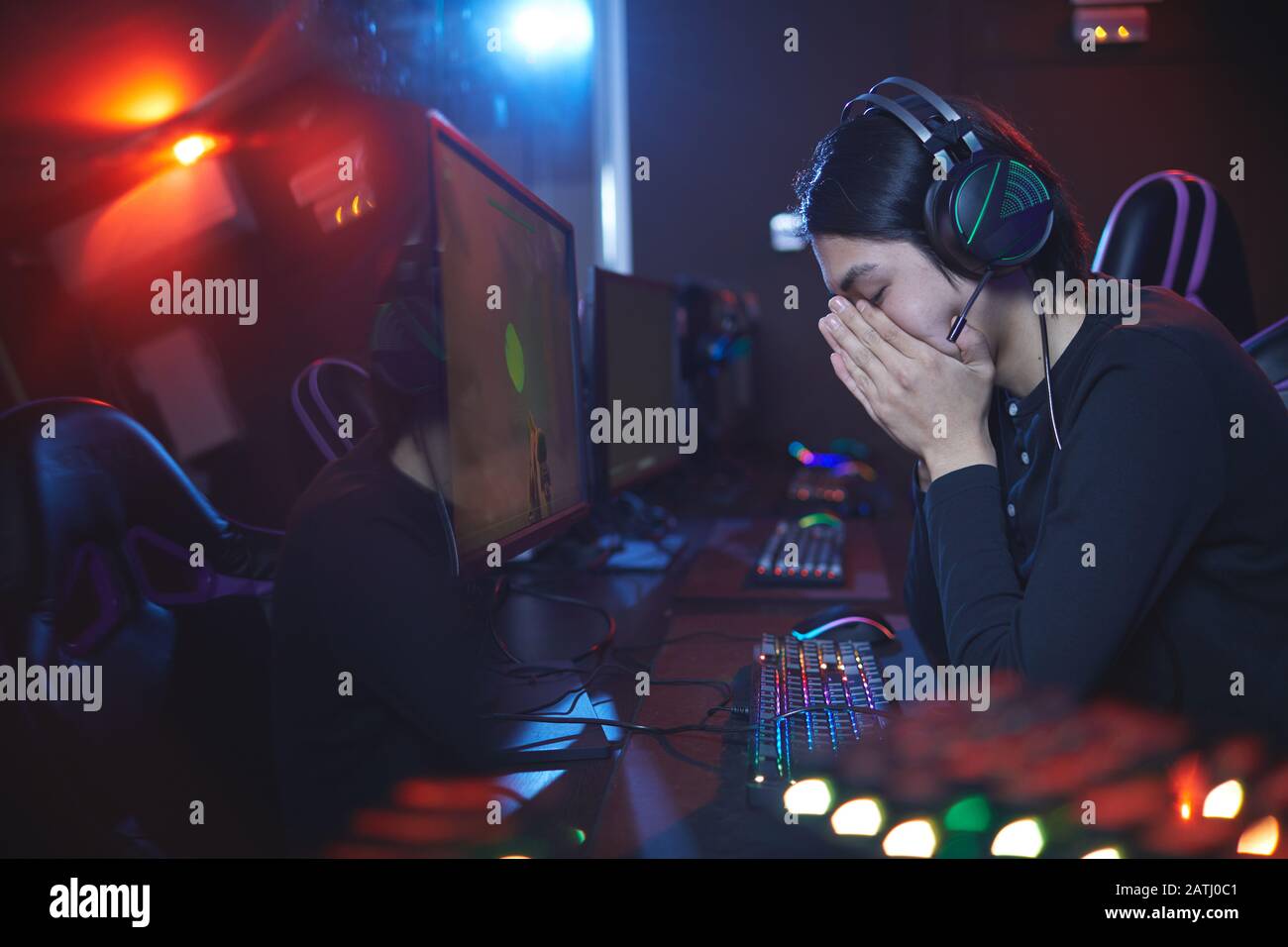 Ritratto della vista laterale di un uomo asiatico frustrato che copre il viso dopo aver perso la competizione di videogiochi, copia spazio Foto Stock