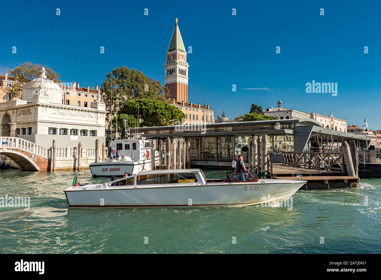 Un taxi acqueo di Venezia con due passeggeri vi condurrà verso il Canal Grande, con il Campanile di San Marco in lontananza, Venezia, Italia Foto Stock