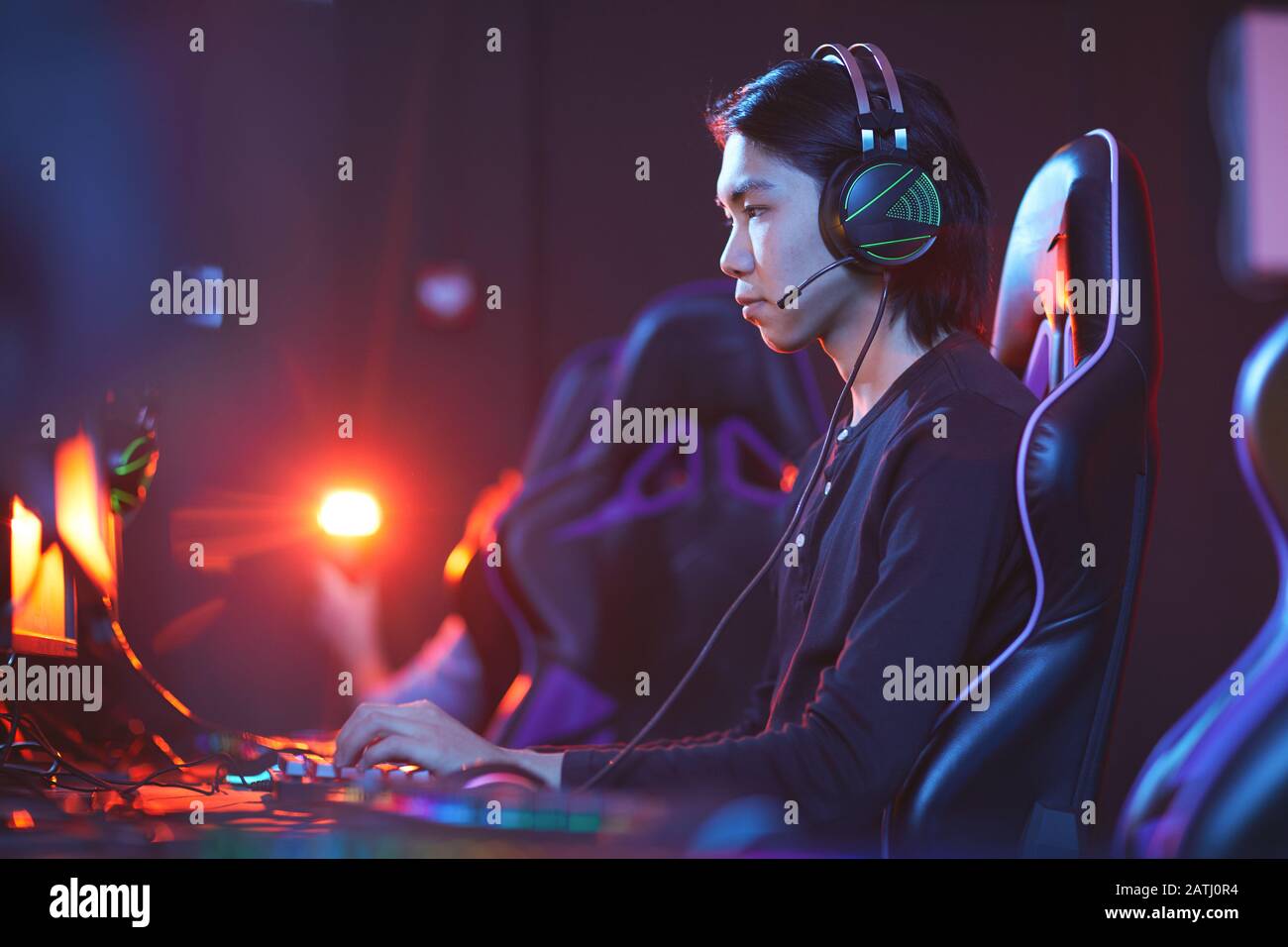Ritratto di un giovane professionista asiatico che gioca a videogiochi in camera oscura, copia spazio Foto Stock