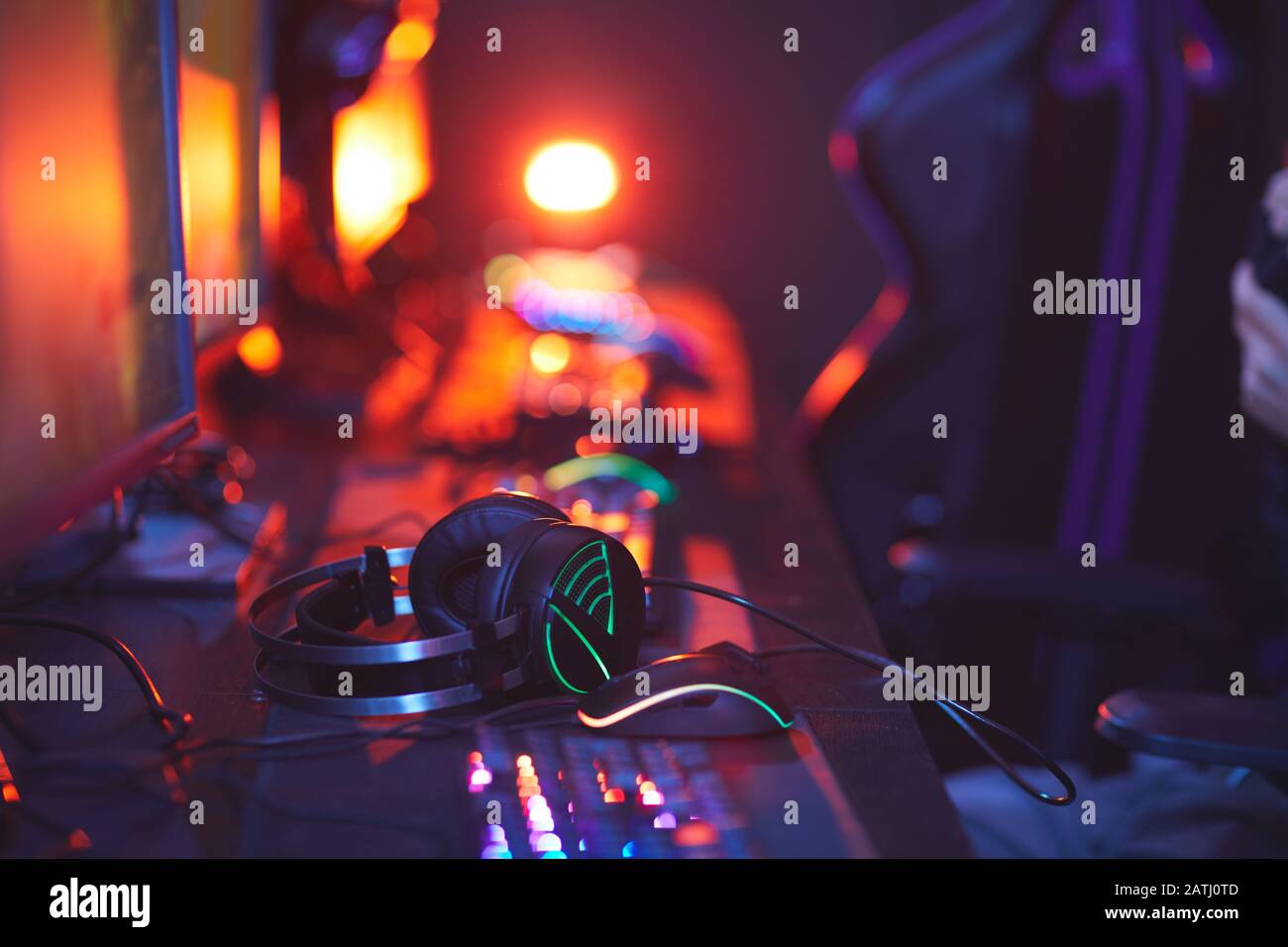 Primo piano delle apparecchiature pro-gaming sulla scrivania del computer, concentrarsi sulle cuffie illuminate e sullo spazio di copia Foto Stock