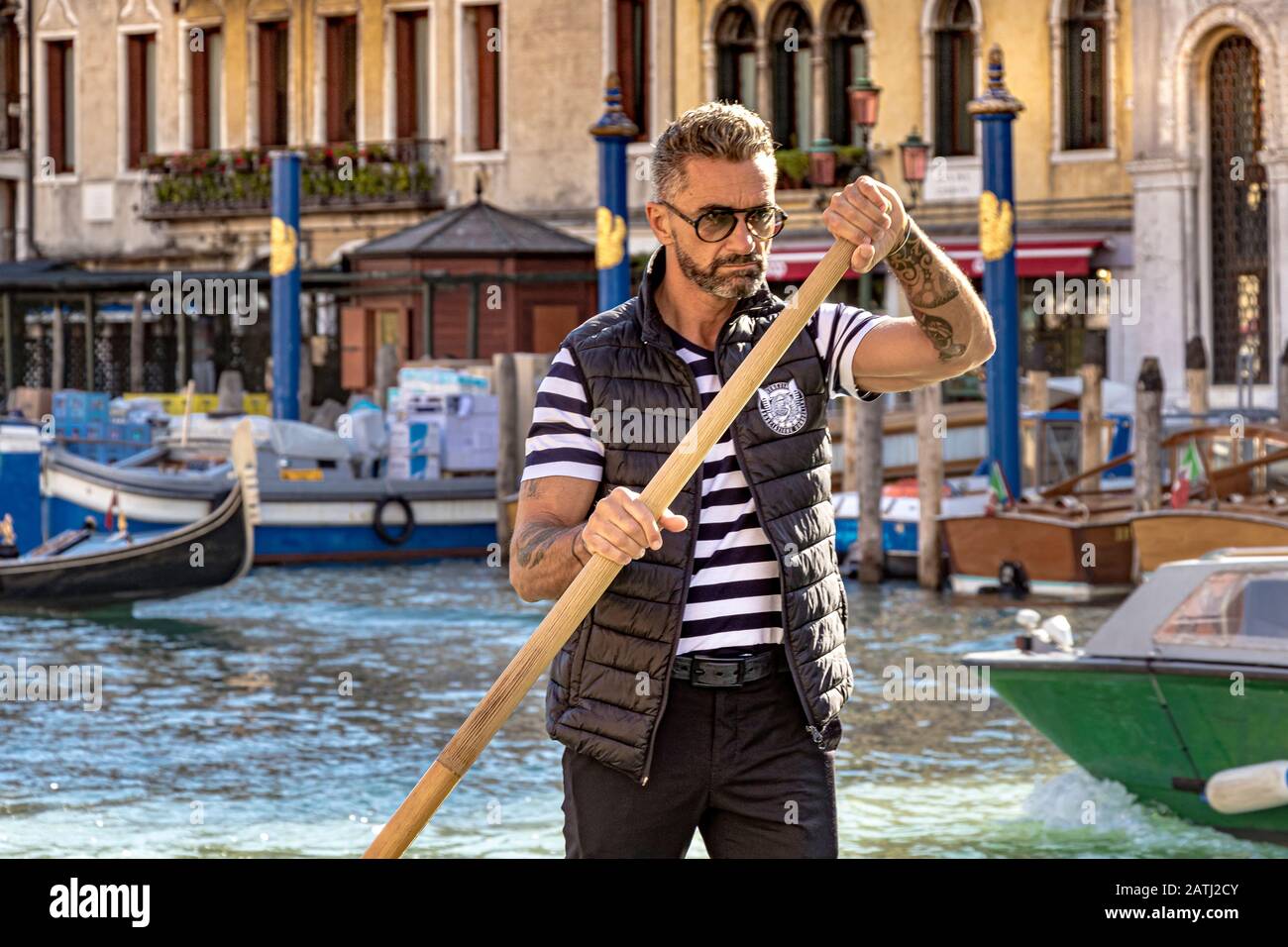 Un Gondoliere a Venezia afferra il suo remo e si concentra sullo sterzo della sua gondola lungo il Canal Grande a Venezia Foto Stock