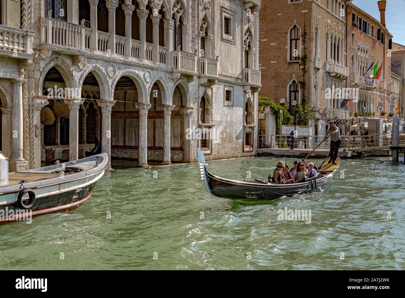 Un gondoliere che porta i turisti per un giro in gondola davanti al Palazzo Gotico Ca' d'Oro, lungo il Canal Grande, Venezia, Italia Foto Stock