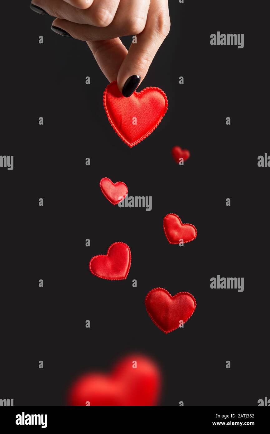 Carta San Valentino. Donna che ha cuori volanti rossi. Isolato su nero. Concetto di amore. Verticale. Foto Stock