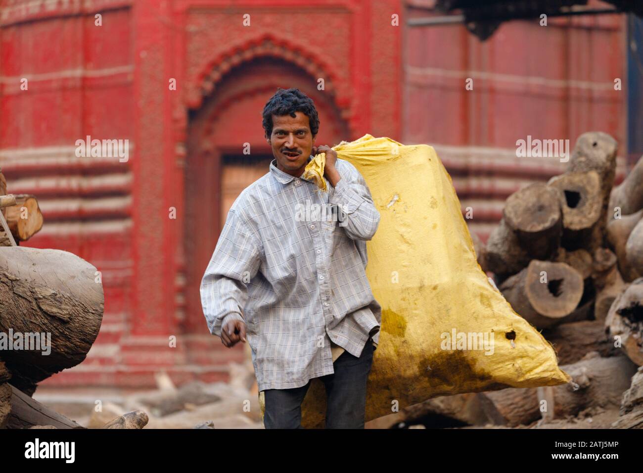 Varanasi, INDIA, 19 GENNAIO 2019 : un uomo sta portando un sacco pieno di tronchi di albero per una cerimonia di cremazione tradizionale lungo il fiume Ganga. Foto Stock