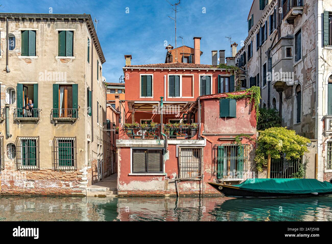 Una coppia che si affaccia dalla finestra del loro appartamento lungo il Rio de la Cazziola e de ca rizzi canale nel quartiere Dorsoduro di Venezia Foto Stock
