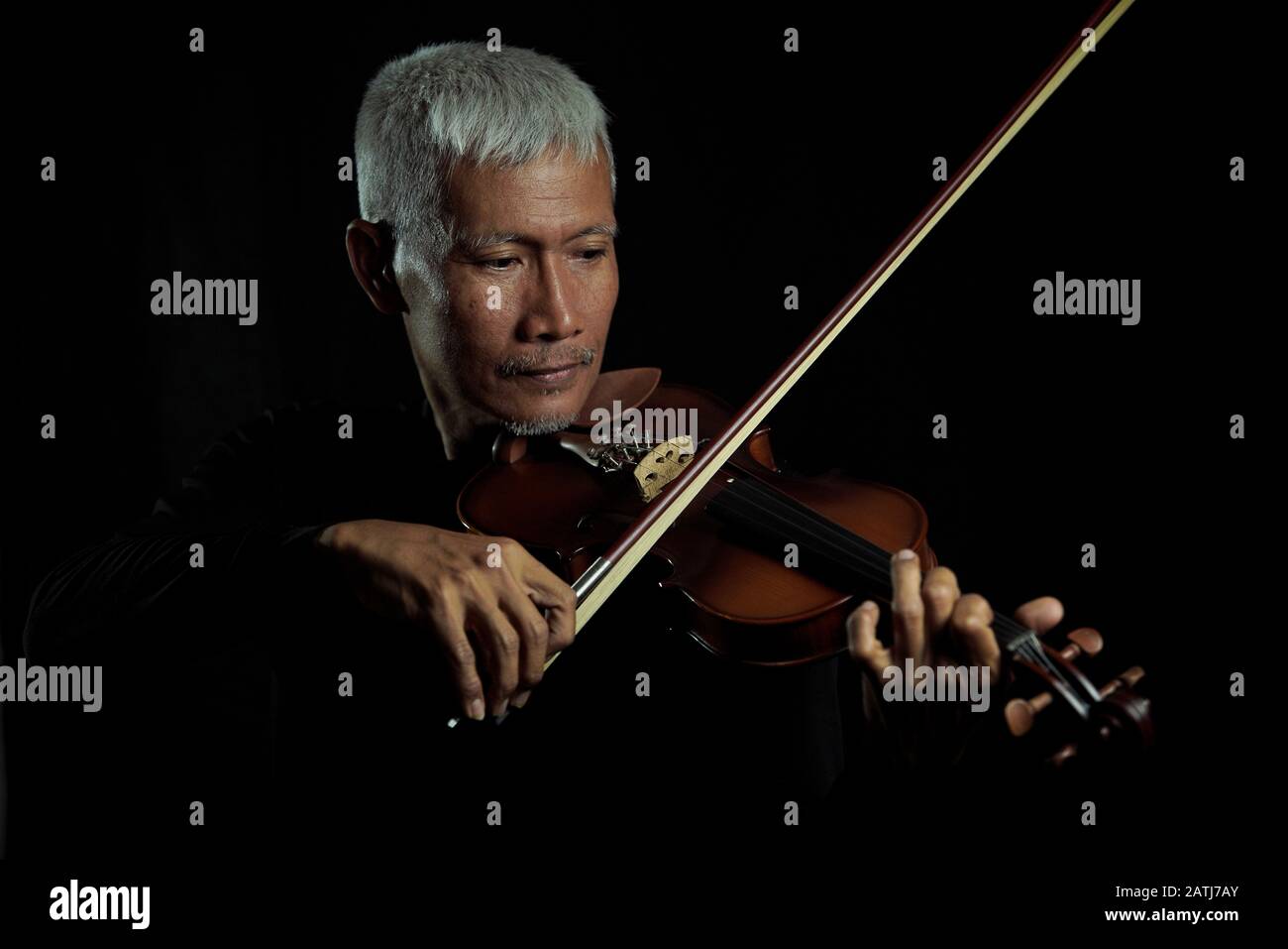 Uomo anziano che suona il violino e si gode la musica su sfondo nero isolato ritratto Foto Stock