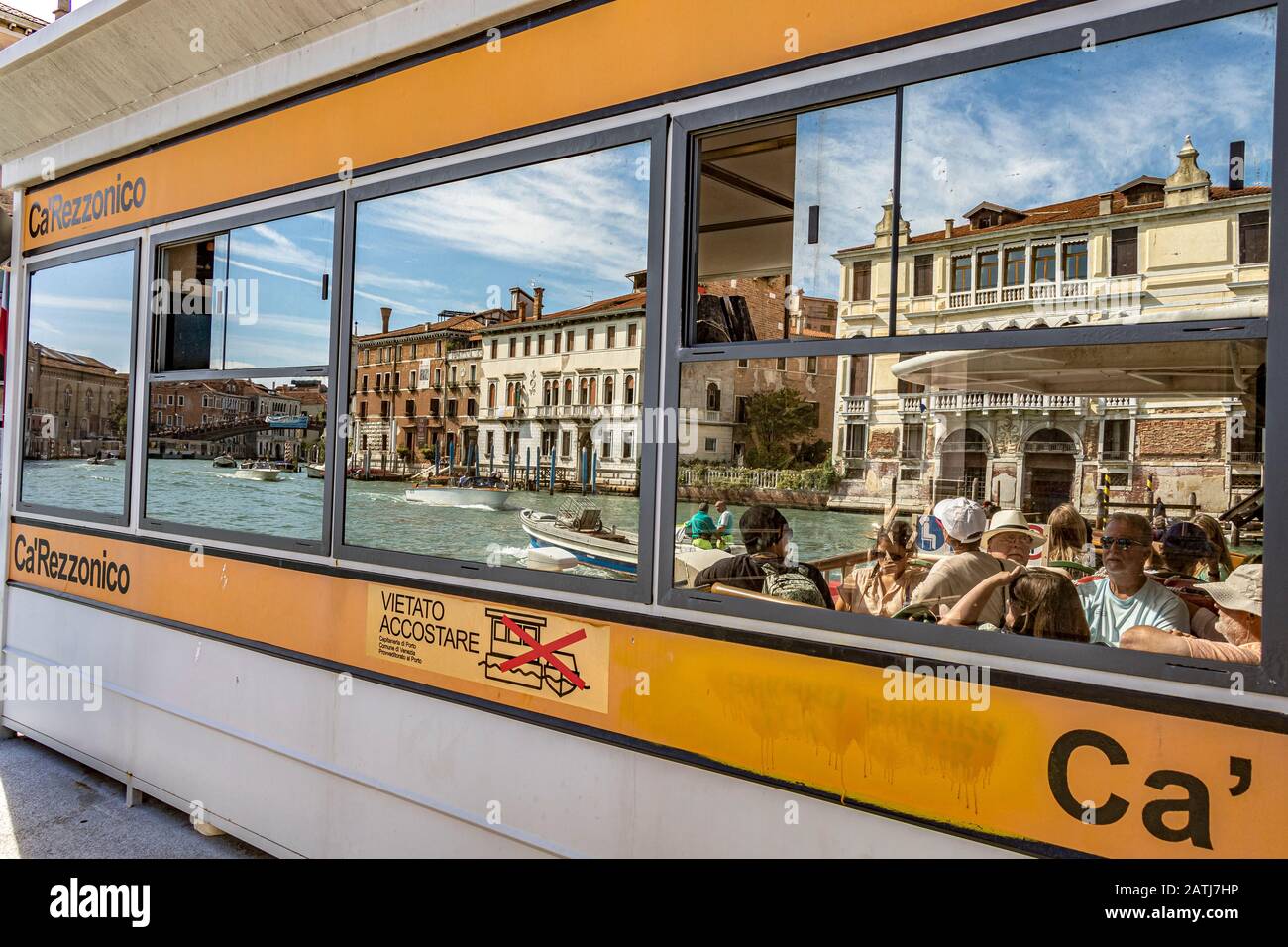 I passeggeri del vaporetto o del vaporetto si riflettono nelle finestre di vetro della fermata Ca' Rezzonico del vaporetto sul Canal Grande, Venezia, Italia Foto Stock