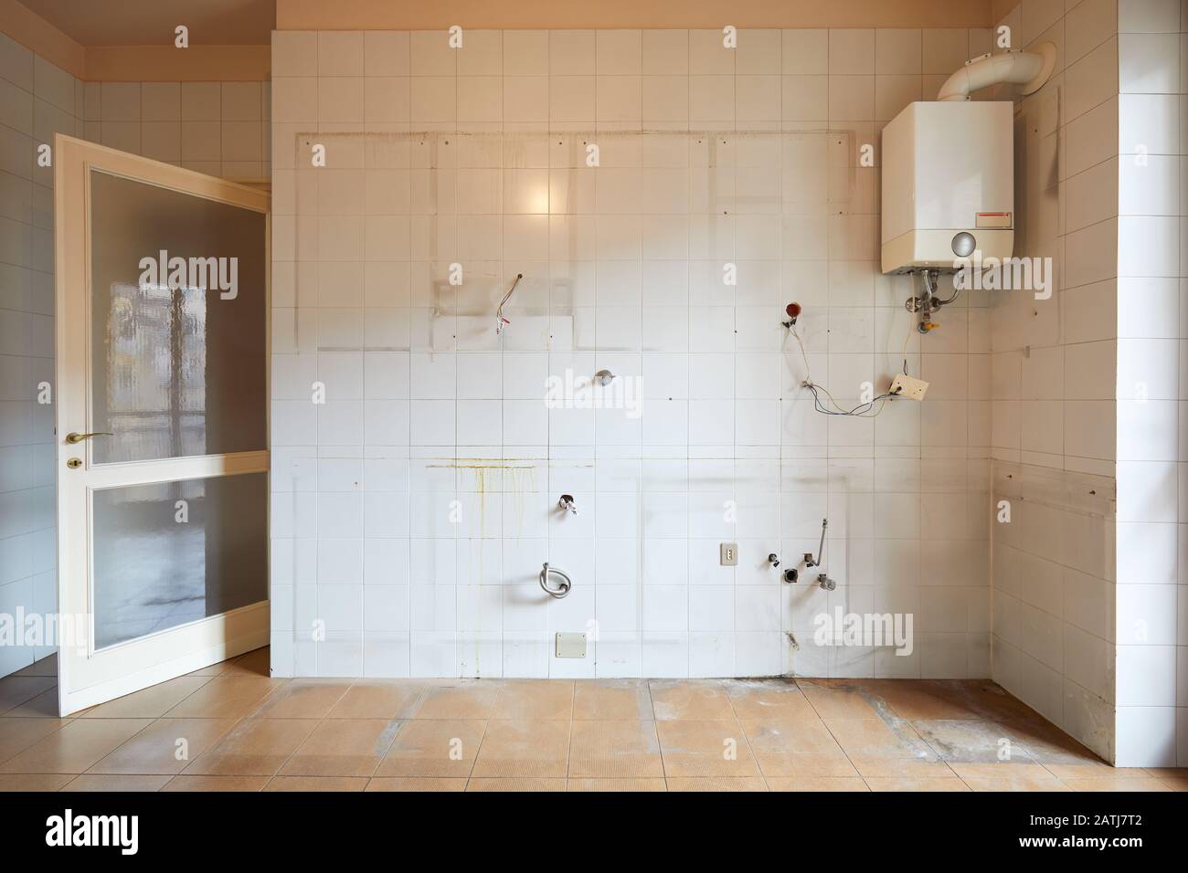 Vecchio muro di cucina vuoto con piastrelle bianche e sporche all'interno dell'appartamento Foto Stock