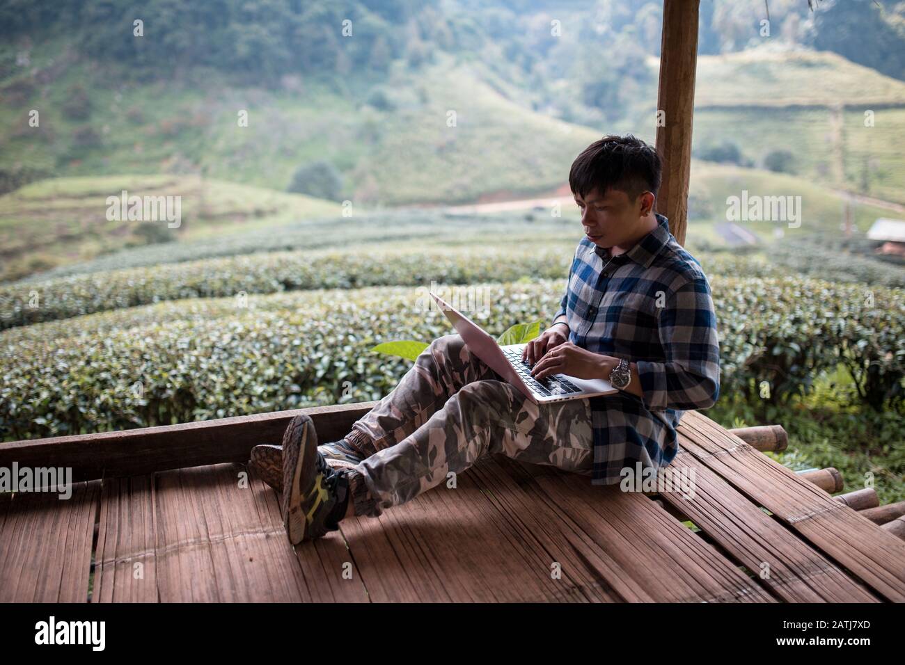 Il blogger seduto in un cottage al campo di tè verde e controllare Mail o scrivere contenuti turistici in Chiang mai Thailandia. Foto Stock