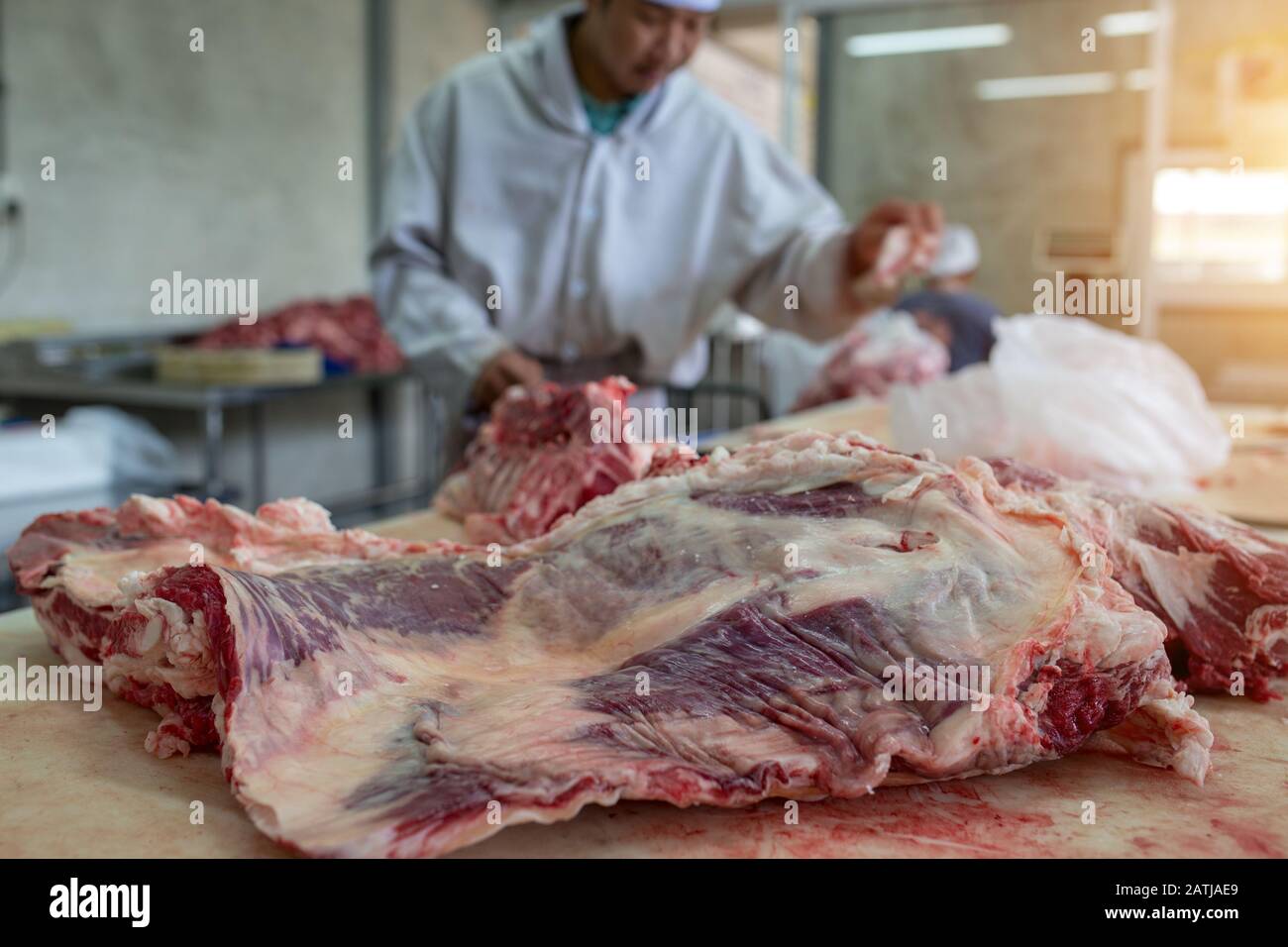Il macellaio che taglia carni bovine crude nel macelleria o nel macello Thailandia. Foto Stock