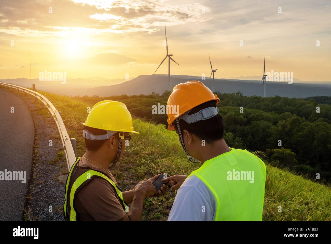 Due ingegneri utilizzano i telefoni cellulari per analizzare i problemi o testare l'energia dalle turbine eoliche che generano elettricità. Foto Stock