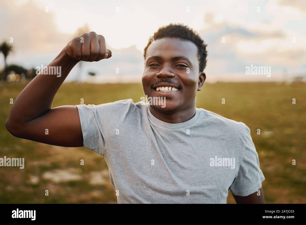 Ritratto di un giovane atleta allegro sorridente e dando punch davanti alla macchina fotografica al parco Foto Stock