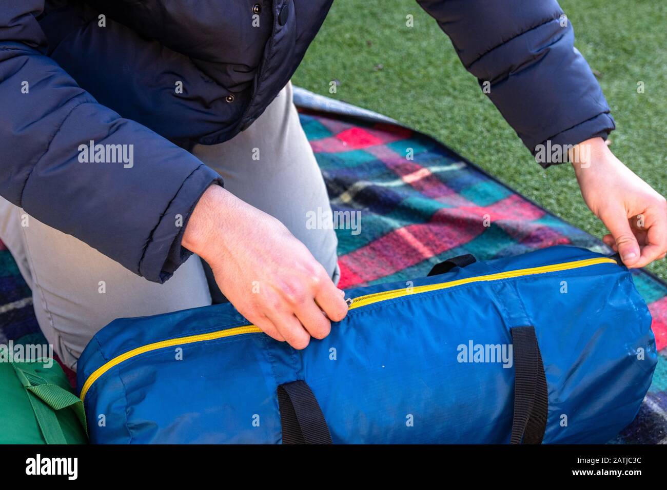 Giovane caucasico sbloccando la tenda sacchetto e campo nel suo proprio giardino. Economico amichevole campeggio e soluzioni di vacanza. Foto Stock