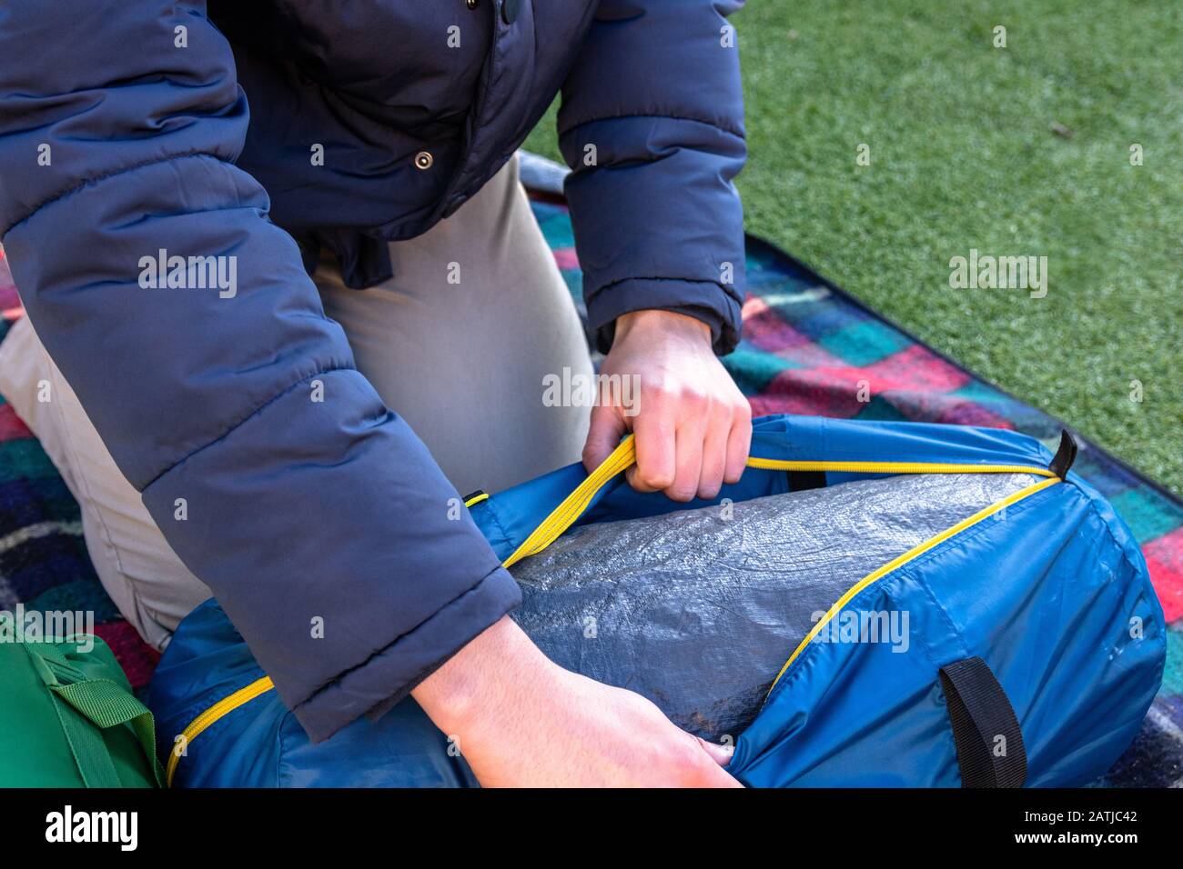 Giovane caucasico sdisimballare la tenda sacchetto e campeggio nel suo proprio giardino. Economico amichevole campeggio e soluzioni di vacanza. Foto Stock
