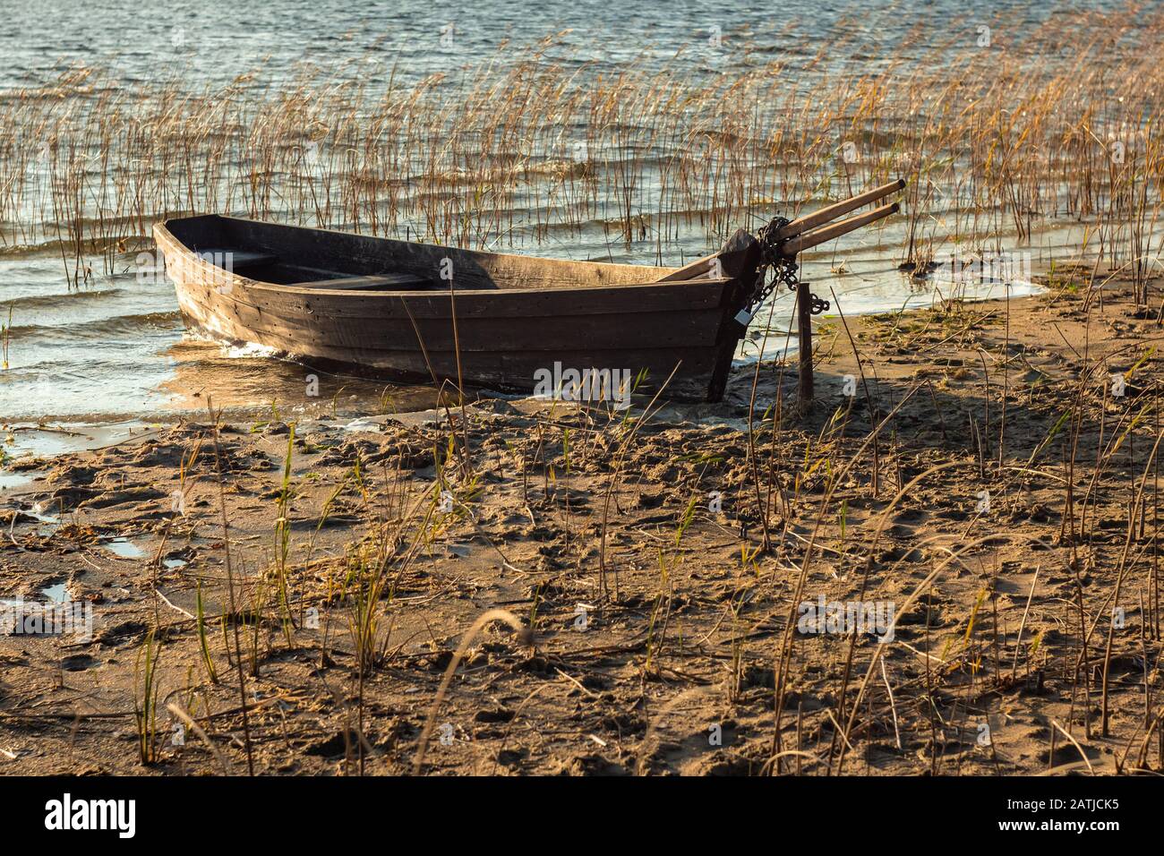 Vecchia barca di legno ormeggiata sul lago di terra della muffa Foto Stock