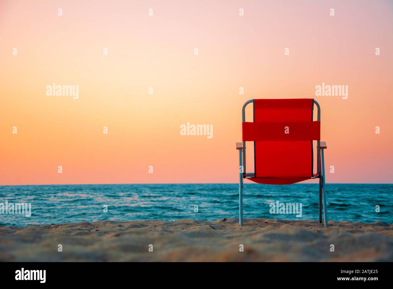 Sedia rossa sulla spiaggia con tramonto rosso Foto Stock