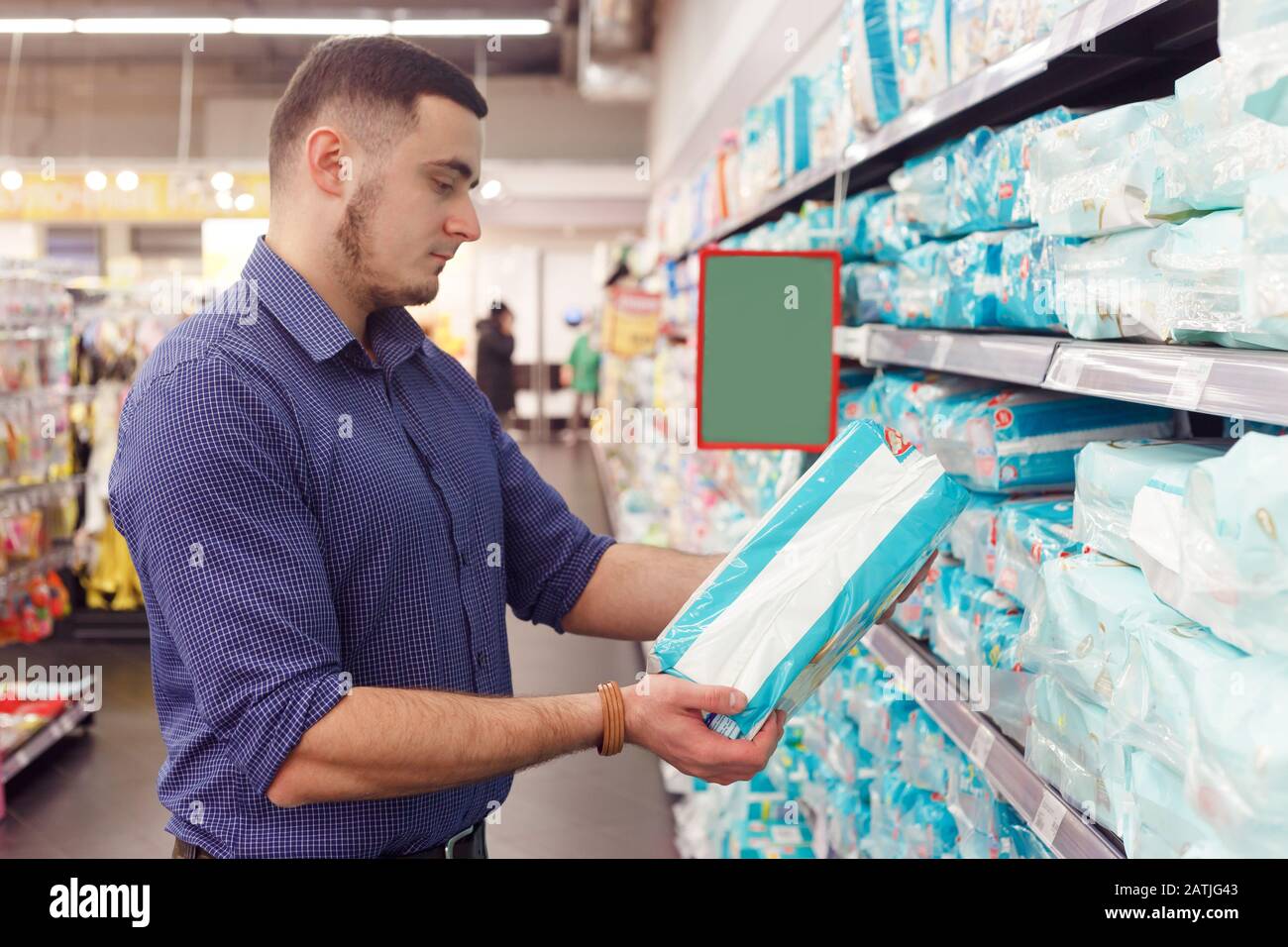 uomo con confezione pannolino in supermercato lettura informazioni sul prodotto Foto Stock